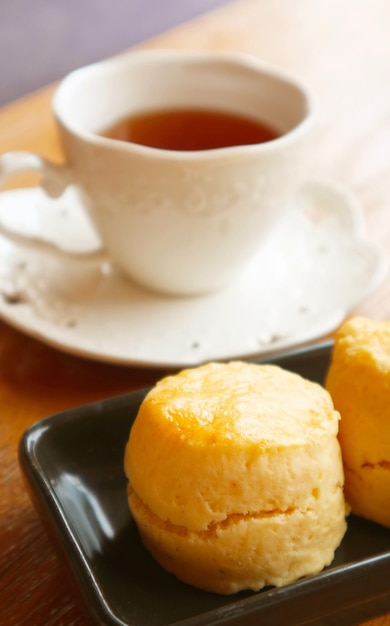 Photo vue rapprochée d'un délicieux scone avec une tasse de thé floue en arrière-plan