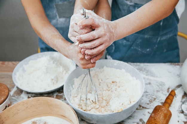 Vue rapprochée de deux petites filles en uniforme de chef bleu qui préparent de la nourriture dans la cuisine