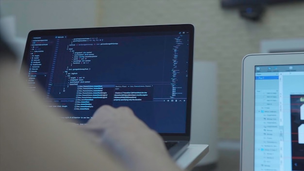Vue rapprochée des développeurs Web en train de programmer JavaScript, de coder HTML sur un ordinateur portable, vue de l'arrière