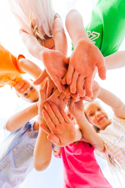 Vue rapprochée du bas des mains des enfants, paume vers le bas, posées l'une sur l'autre. Enfants marquant la fin du jeu, mettant leurs mains ensemble