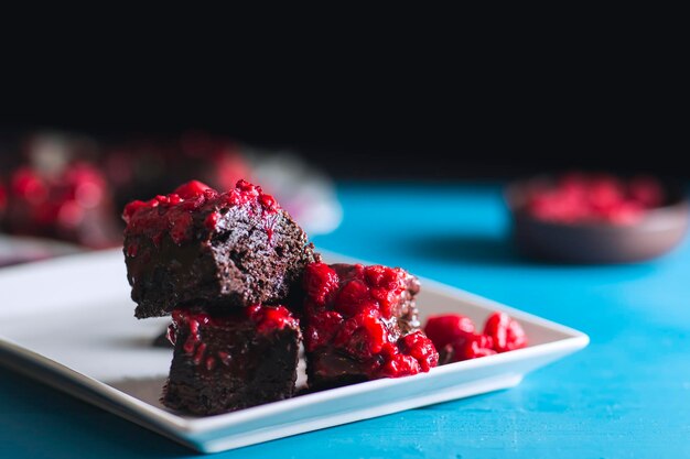 Vue rapprochée du brownie aux framboises fait maison sans gluten sur une table en bois vintage bleue