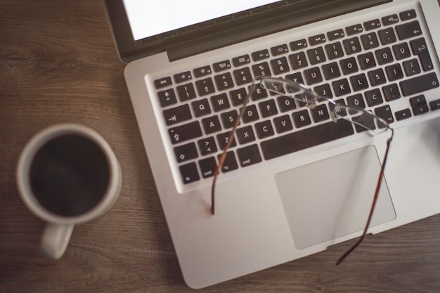 Vue rapprochée du café et de l'ordinateur portable avec des lunettes sur la table