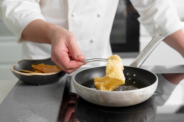 Vue rapprochée du chef masculin cuisine sur poêle à frire.