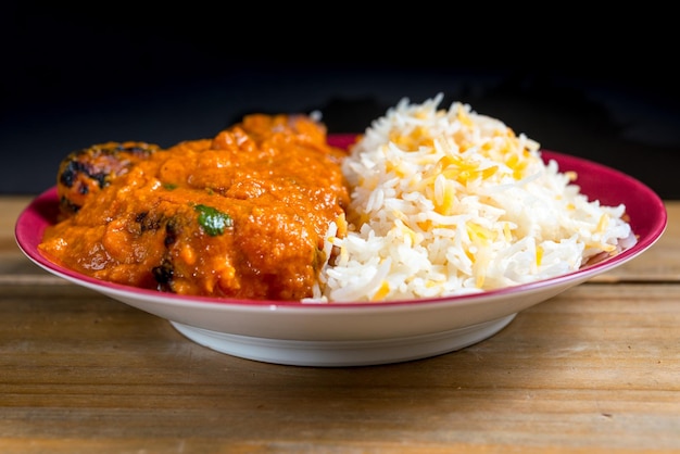 Vue rapprochée du curry et du riz servis dans une assiette sur table sur un fond noir