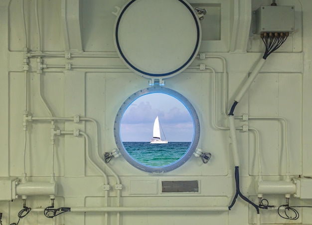 Photo vue rapprochée du hublot sur un bateau de croisière avec vue sur l'océan et le yacht