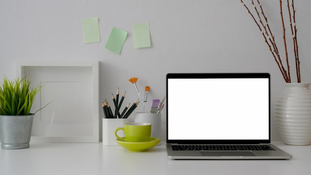 Vue rapprochée du lieu de travail avec un ordinateur portable à écran blanc