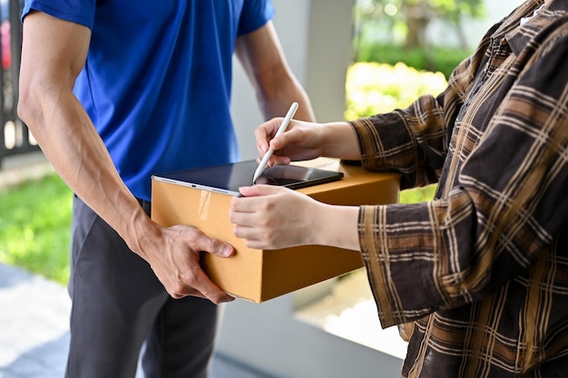 Vue rapprochée du livreur, demandez à son client de signer sur une tablette pour le colis