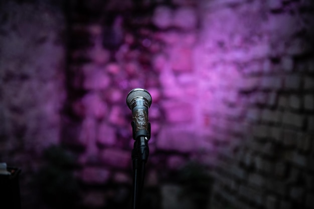 Photo vue rapprochée du microphone contre un mur violet éclairé