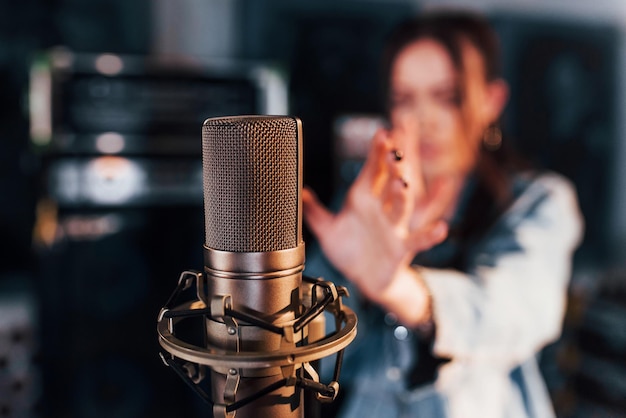 Vue rapprochée du microphone Jeune belle interprète féminine répétant dans un studio d'enregistrement