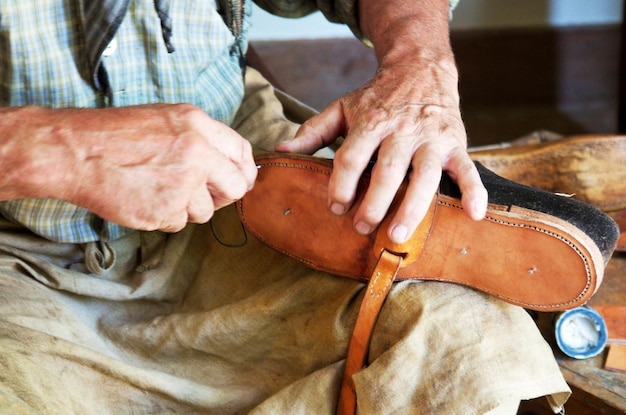 Vue rapprochée du milieu d'un homme cousant une chaussure