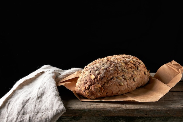 Photo vue rapprochée du pain sur la planche à couper sur un fond noir