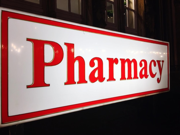Photo vue rapprochée du panneau rouge de la pharmacie sur le mur la nuit