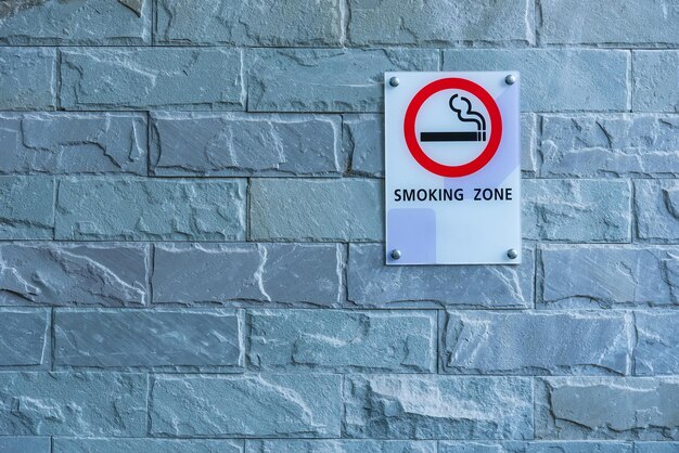 Photo vue rapprochée du texte de la zone fumeurs sur le panneau d'information contre le mur