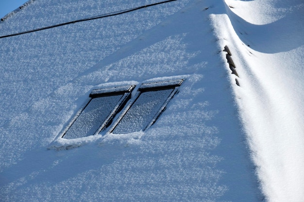Vue rapprochée du toit de la maison avec des fenêtres de grenier couvertes de neige en hiver froid Couverture en tuiles du bâtiment en hiver