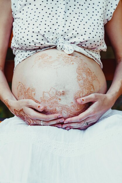 Vue rapprochée du ventre découvert de la femme enceinte, peint avec un motif mehendi