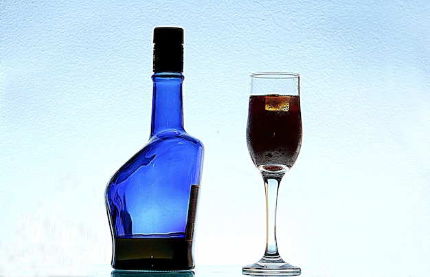 Photo vue rapprochée du verre et de la bouteille d'alcool sur fond blanc