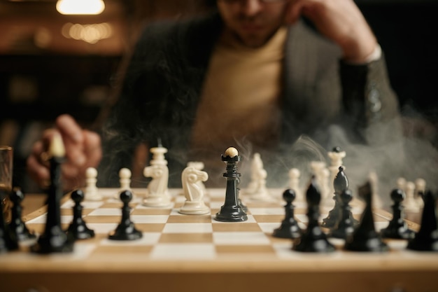 Vue rapprochée sur l'échiquier en fumée avec joueur d'échecs sur fond flou