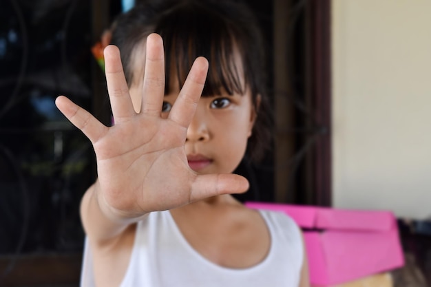 Vue rapprochée d'une enfant montrant la main d'arrêt signalant d'arrêter contre la violence et la douleur