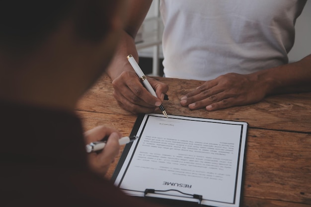 Vue rapprochée de l'entretien d'embauche au bureau, axée sur les conseils de rédaction de CV, l'employeur examine le bon CV d'un recruteur de candidats qualifiés et préparés, envisageant la candidature du responsable des ressources humaines, prenant la décision d'embauche