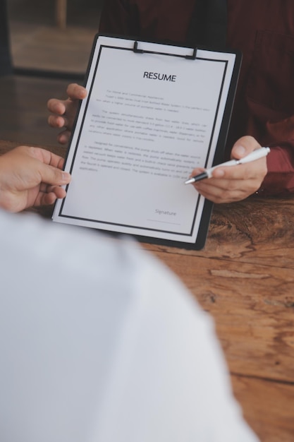 Vue rapprochée de l'entretien d'embauche au bureau, axée sur les conseils de rédaction de CV, l'employeur examine le bon CV d'un recruteur de candidats qualifiés et préparés, envisageant la candidature du responsable des ressources humaines, prenant la décision d'embauche