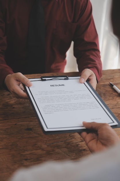 Vue rapprochée de l'entretien d'embauche au bureau, axée sur les conseils de rédaction de CV, l'employeur examine le bon CV d'un recruteur de candidats qualifiés et préparés, envisageant la candidature du responsable des ressources humaines, prenant la décision d'embauche