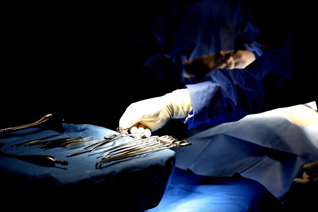 Photo vue rapprochée de l'équipement de prise à la main avec un collègue effectuant une intervention chirurgicale sur un patient