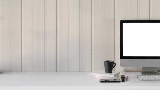 Vue rapprochée de l'espace de travail avec écran d'ordinateur vierge, tasse à café et fournitures de bureau sur tableau blanc avec mur de planche