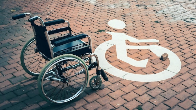 Vue rapprochée d'un fauteuil roulant vide avec un symbole de handicap sur le trottoir