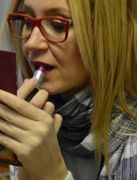 Photo vue rapprochée d'une femme appliquant du rouge à lèvres