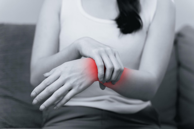 Vue rapprochée d'une femme assise sur le canapé tenant sa blessure au poignet avec une lumière rouge
