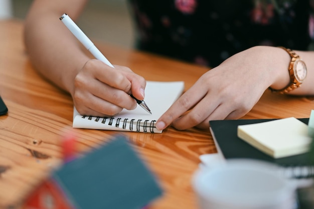 Vue rapprochée femme créative prenant des notes sur un ordinateur portable.