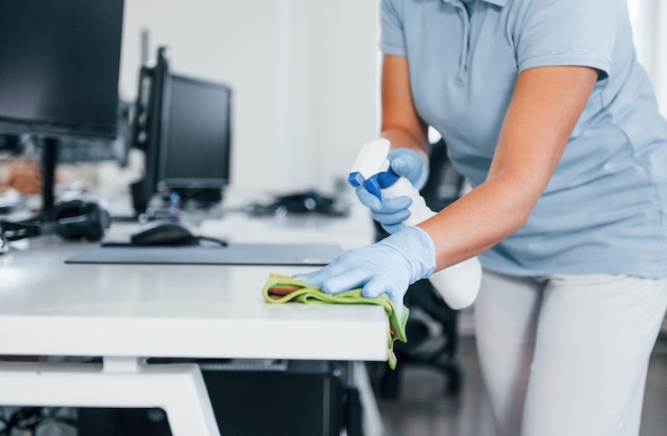 Photo vue rapprochée de la femme dans des gants de protection qui nettoient les tables au bureau