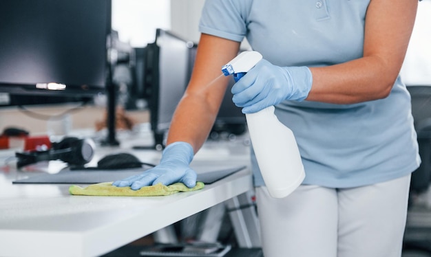 Vue rapprochée de la femme dans des gants de protection qui nettoient les tables au bureau