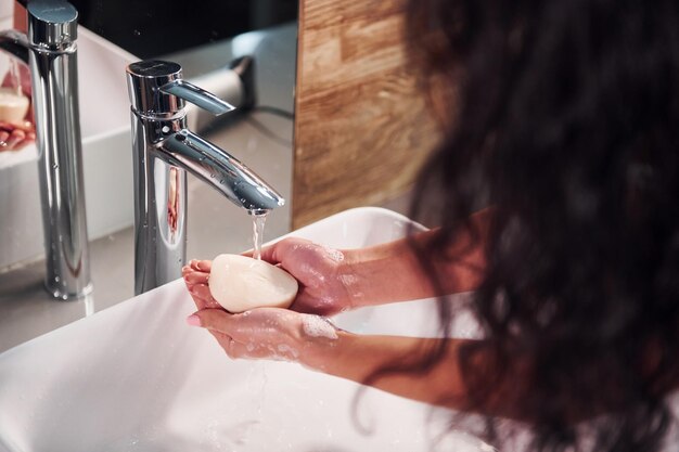 Vue rapprochée d'une femme debout dans la salle de bain et se lavant les mains.