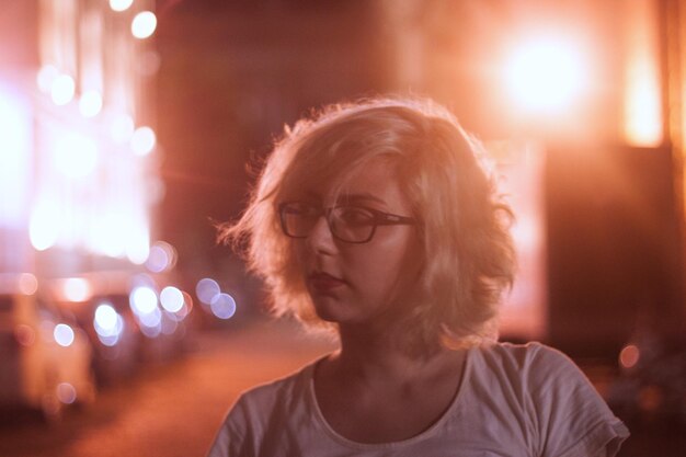 Photo vue rapprochée d'une femme détournant son regard dans la rue de la ville la nuit