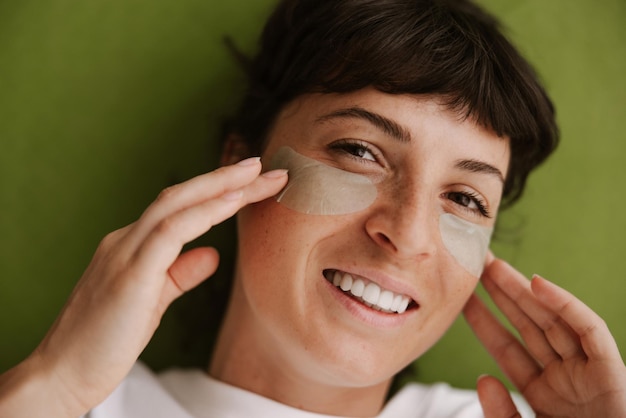 Vue rapprochée d'une femme fraîche souriante regarde la caméra avec des patchs pour les yeux