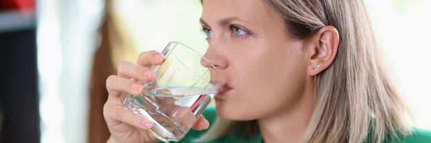Vue rapprochée d'une femme malheureuse avec un visage sérieux buvant de l'eau non gazeuse déshydratation santé
