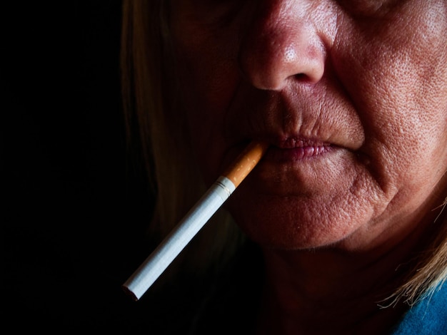 Vue rapprochée d'une femme mature fumant une cigarette