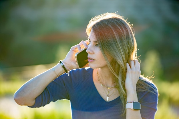 Photo vue rapprochée d'une femme qui parle au téléphone portable à l'extérieur dans la nature en rétroéclairage technologie