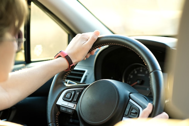 Vue rapprochée d'une femme tenant un volant au volant d'une voiture dans la rue par une journée ensoleillée