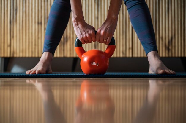 Vue rapprochée d'une femme travaillant à la maison avec un poids de kettlebell