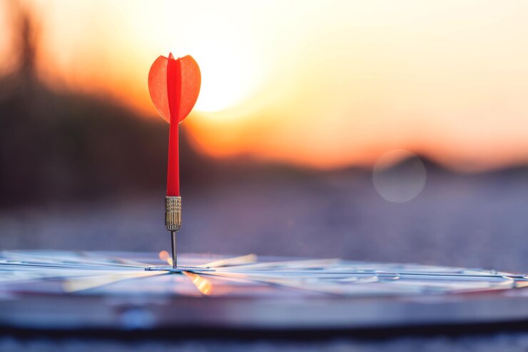 Photo vue rapprochée de la flèche rouge frappant le dartboard central contre le ciel au coucher du soleil