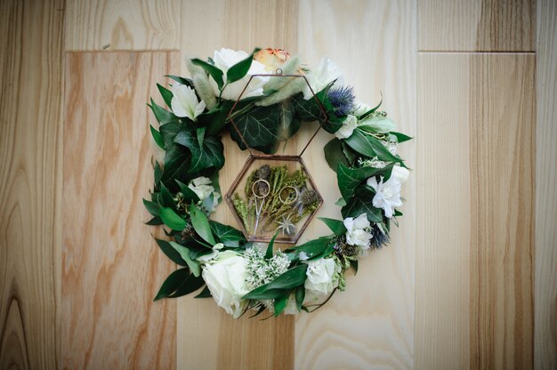 Vue rapprochée de fleurs blanches, anneaux de mariage dans une boîte rustique avec des plantes à l'intérieur