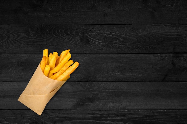 Vue rapprochée des frites croustillantes isolées sur une table en bois noir