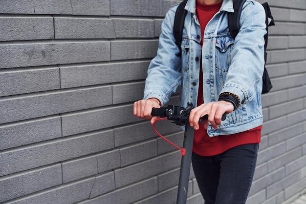 Vue rapprochée d'un gars en vêtements décontractés qui fait du scooter électrique à l'extérieur pendant la journée ensoleillée