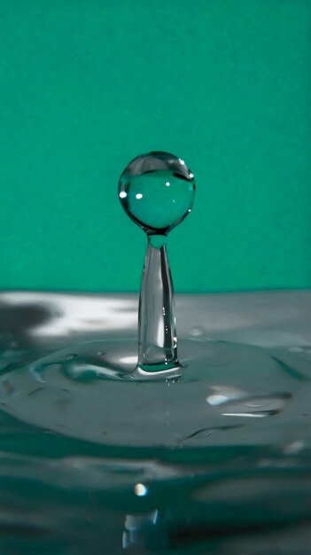 Photo vue rapprochée d'une goutte tombant dans l'eau sur un fond turquoise