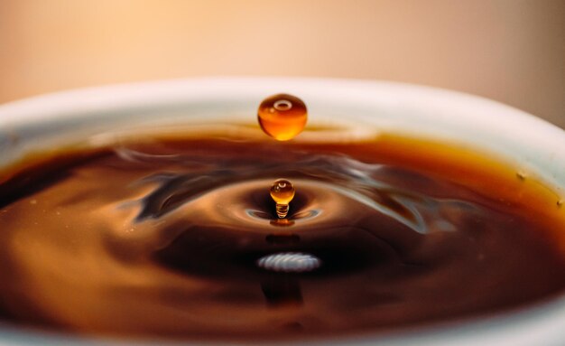 Vue rapprochée des gouttes de café qui tombent dans la tasse de café