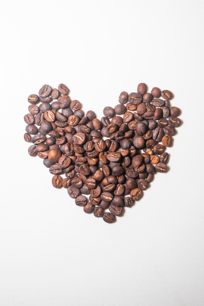 Vue rapprochée de grains de café torréfiés sur un fond blanc