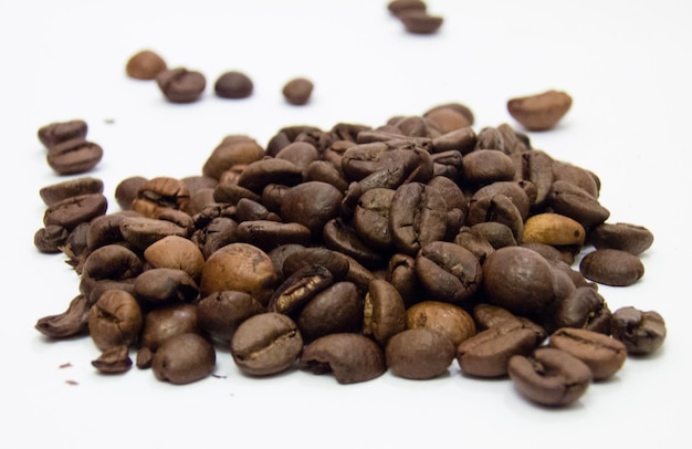 Vue rapprochée de grains de café torréfiés sur fond blanc