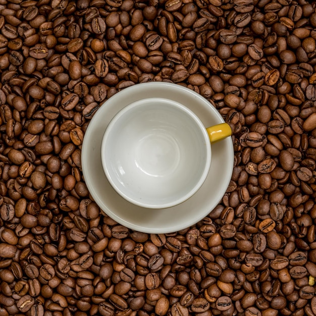 Vue rapprochée de grains de café torréfiés avec des tasses